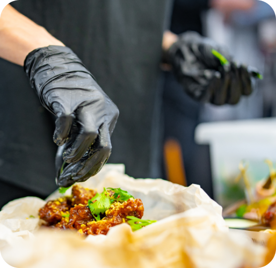 Close-up of food being garnished during preparation in a fast casual kitchen environment.