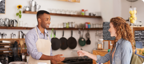 Customer completing a payment transaction with a staff member at a food and beverage service counter.